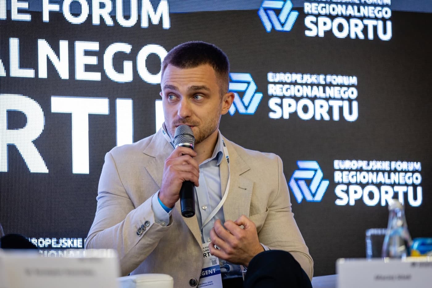 Rafał z mikrofonem na panelu Europejskiego Forum Regionalnego Sportu