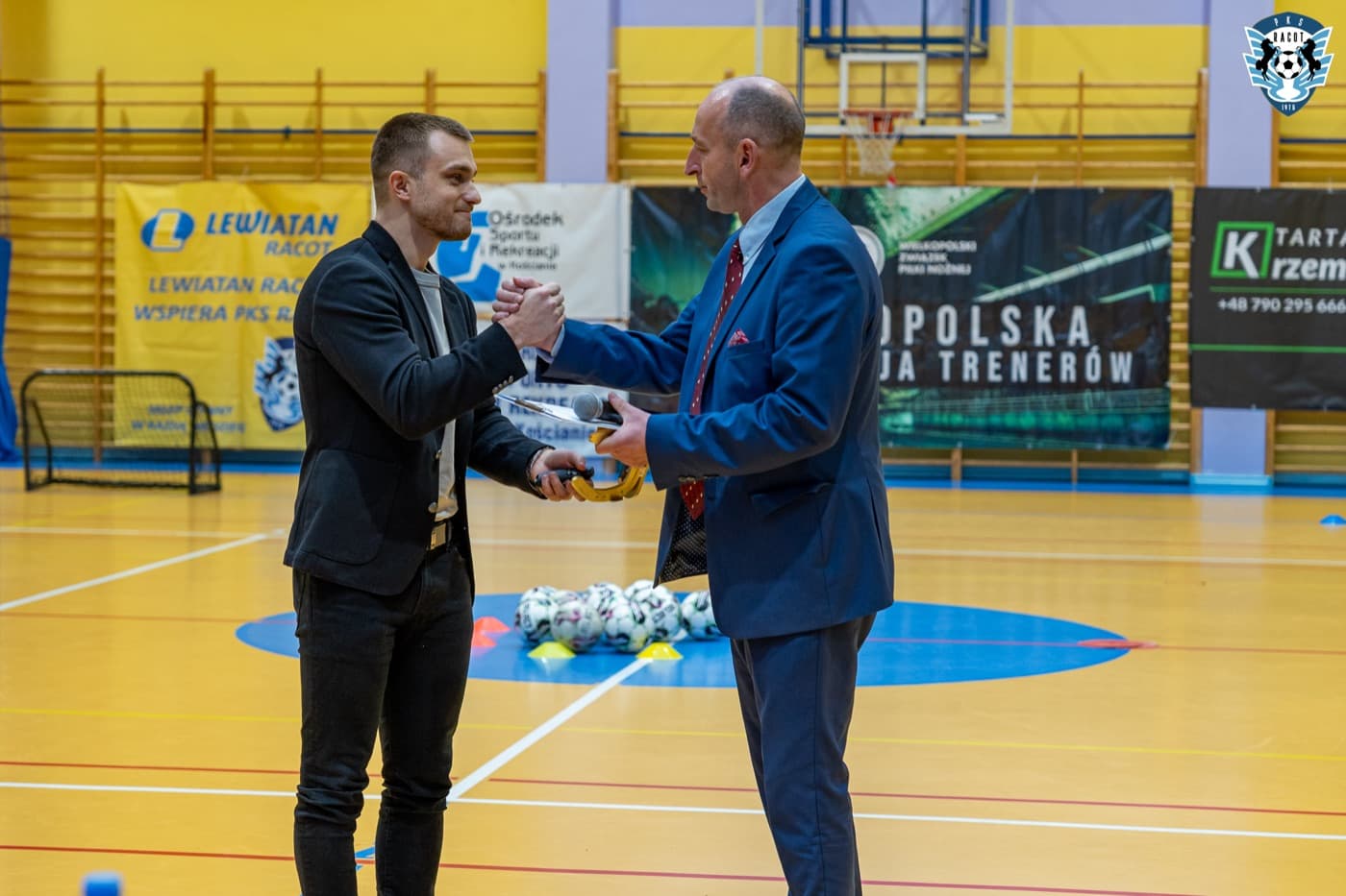Rafał odbiera podziękowanie na konferencji w hali sportowej